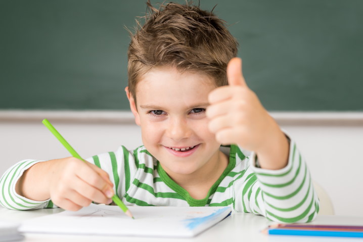 Junge in Schule zeigt Daumen hoch